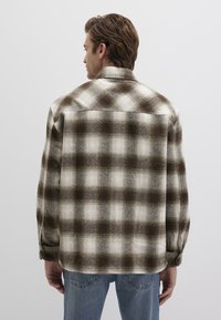 Karierter Hemd in erdigen Tönen von Grün und Creme, aus strukturiertem Stoff. Es verfügt über einen knöpfbaren Bund und ein klassisches Kragen-Design.