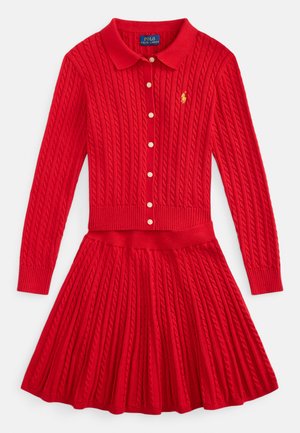 Vestito rosso a maglia con collo e bottoni sulla parte superiore e gonna plissettata. La trama presenta dettagli a trecce e un accento con logo.