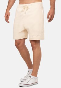 Beige katoenen shorts met een elastische tailleband en koord, voorzien van zijzakken en subtiele logo borduursels nabij de zoom.