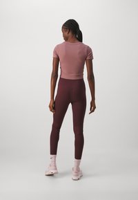Sportlik riietus, mis sisaldab hästi istuvat lühikeste varrukatega mauve'i särki, kõrge vöökohaga burdeos värvi retuuse ja helesiniseid sneakers'eid. Lihtne disain.