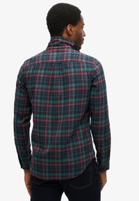 Geruit overhemd met lange mouwen in een patroon van groen, marineblauw en bordeauxrood. Ontworpen met een button-down kraag en afgeronde zoom.