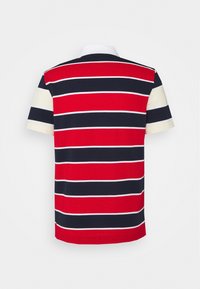 Polo à manches courtes avec larges rayures horizontales rouges, noires et blanches et col blanc, vu de dos.