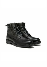 Bottes en cuir noir à finition lisse, avec lacets sur le devant et fermeture éclair latérale, accents texturés et semelles épaisses à crampons.