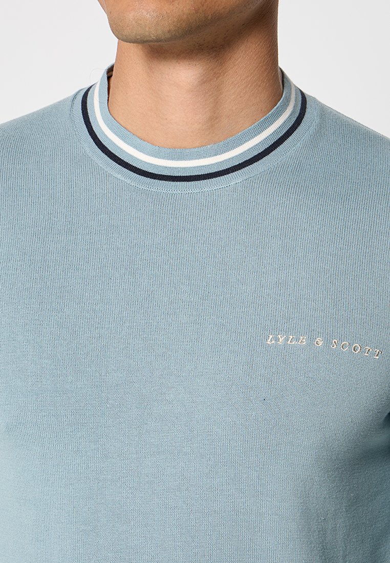 Maglione a coste di colore azzurro chiaro con scollo rotondo. Presenta un colletto a righe bianche e blu navy e un piccolo logo "LYLE & SCOTT" in oro.
