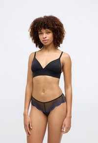 Čierny bralet s dizajnom do V a nastaviteľnými ramienkami, skombinovaný s čiernymi sieťovanými nohavičkami s vykrojeným modrým čipkovým olemovaním.