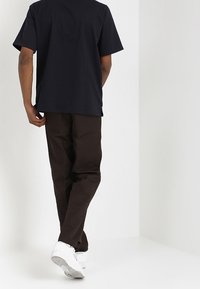 Camiseta de manga corta de color marino con cuello redondo, combinada con pantalones marrones y zapatillas blancas. El tejido parece suave y casual.