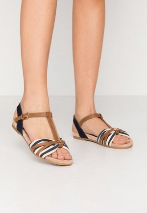 Sandaal met bandjes in een kleurencombinatie van bruin en marineblauw, met een gestreepte stoffen bovenzijde, platte zool en sierlijke hardware detail.