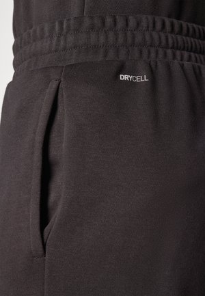 Pantaloni sportivi neri realizzati in tessuto testurizzato con vita elasticizzata, tasche laterali e un'etichetta "DRYCELL" vicino alla tasca.