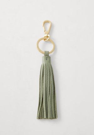 Porte-clés avec un fermoir en métal doré et un anneau circulaire, orné d'une frange en cuir vert avec plusieurs fils fins et une texture lisse.