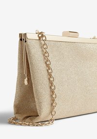Gold glitter clutch bag with a metal chain strap, framed closure, and textured surface, featuring a rectangular shape and soft edges.