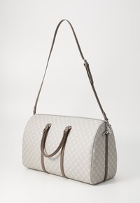 Sac de sport gris clair avec une surface texturée, comportant un motif répétitif, des accents en cuir brun, des poignées supérieures doubles et une bandoulière amovible.