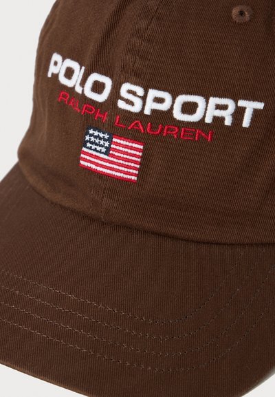 Brown cap with white "POLO SPORT" text, red "RALPH LAUREN" text, and a small embroidered American flag on the front panel.