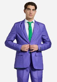 Completo viola a righe sottili con design a un bottone, cravatta verde con motivo testurizzato e bottoni neri a contrasto sui polsini.