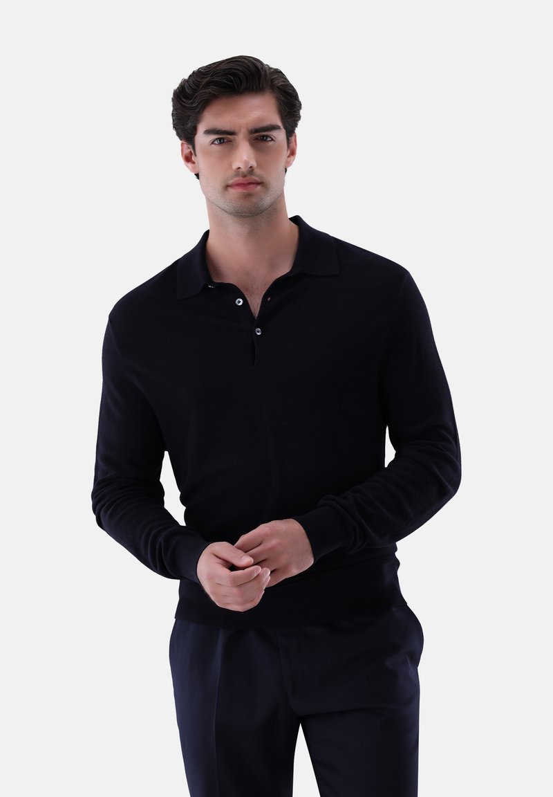 Schwarzes langärmliges Polohemd mit Kragen, zwei-Knopf-Leiste, gerippten Bündchen und glatter Textur. Getragen über dunklen Hosen.