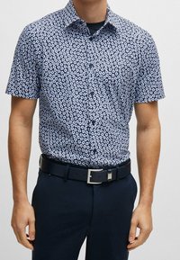Košile na knoflíky s krátkým rukávem, s námořnickým modrým pozadím a bílým květinovým vzorem, vyrobená z lehkého materiálu, s klasickým límcem.