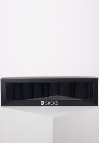Dunkelmarineblaue Socken in einer transparenten Box, mit sechs Paaren ordentlich gestapelt. Die Verpackung hat ein schwarzes Design mit weißem Text.