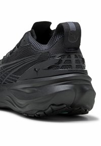 Black athletic shoe with knit fabric upper, sleek design, padded collar, TPU accents, and a distinctive textured sole for grip.