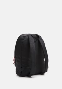 Sac à dos noir avec un design élégant et arrondi. Fabriqué en matériau durable, il est doté de bretelles rembourrées et d'un détail de fermeture éclair rouge.