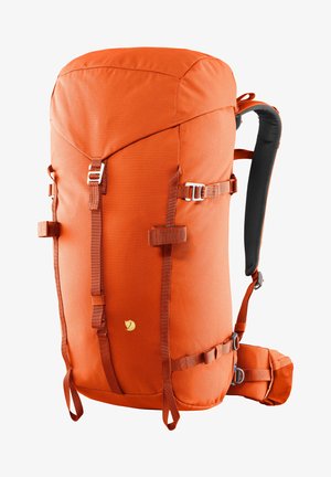 Oranger Stoffrucksack mit verstellbaren Trägern, silbernem Zubehör und einem auffälligen Logo. Verfügt über eine gebogene Oberseite und seitliche Kompressionsriemen.