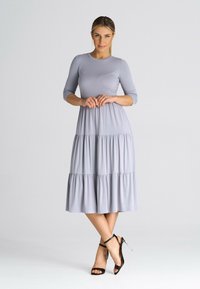 Szara, warstwowa maksi sukienka z rękawami do łokci i okrągłym dekoltem. Zestawiona z czarnymi sandałami na obcasie. Gładka, miękka struktura tkaniny.