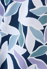 Textielstof met een donkerblauwe achtergrond en overlappende bladeren in lichtgroene, lavendelkleurige en witte tinten, omlijnd in het wit.