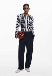 Mustavalkoruudullinen pitkähihainen paita, lyhyt malli, yhdistetty tummansinisiin leveälahkeisiin housuihin ja punaiseen kirjekuorilaukkuun, jossa valkoisia yksityiskohtia.