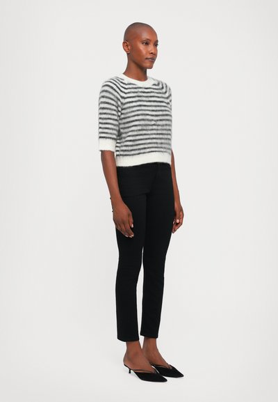Gestreepte trui in grijs en wit, met korte mouwen en een wijde halslijn. Draagt met zwarte slim-fit broek en zwarte puntige hakken.