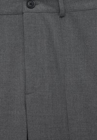 Grijze formele broek met een zwarte knop en riemlus, met zichtbare voorplooien en details van de stoftextuur.