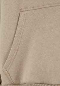 Khaki Sweatshirt-Stoff mit Taschen-Detail. Die Textur ist glatt mit einer genähten Naht und geripptem Saum. Subtile Farbvariation.