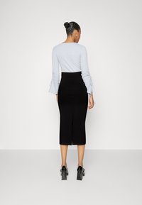 Light blue ribbed long-sleeve top with gathered details at the cuffs, paired with a black pencil skirt featuring a back slit and high waist.