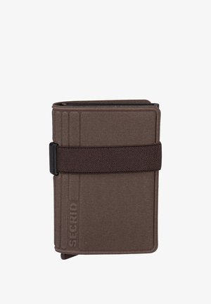 Cartera marrón con textura de tela y cierre de correa oscura. Presenta un diseño minimalista y una marca en relieve en un lado.