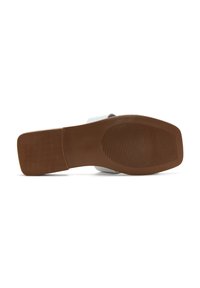 Semelle en caoutchouc marron avec une texture antidérapante, attachée à un dessus blanc à la finition lisse et au design de bande. Profil plat et large.