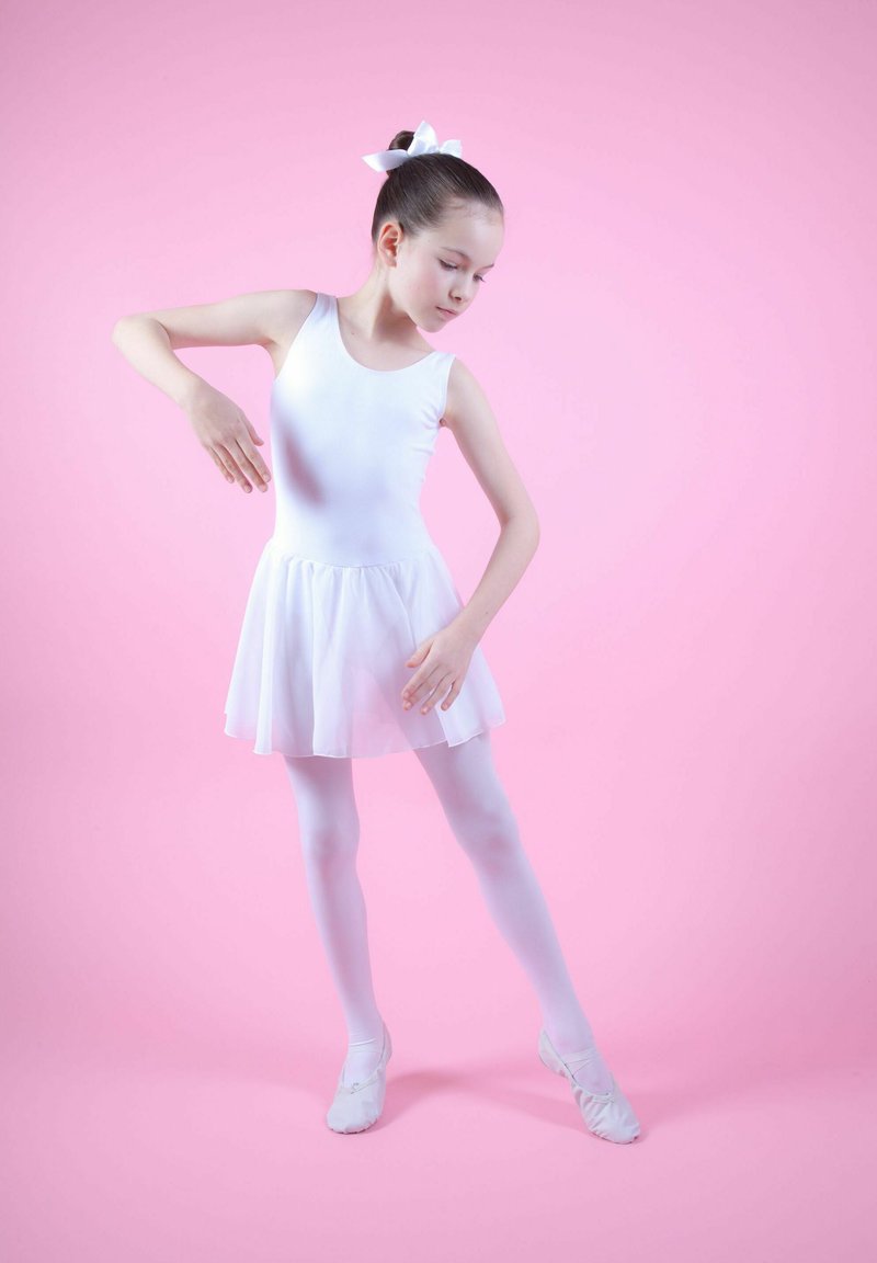 Weißes Ballettkleid mit einem transparenten Rock, kombiniert mit weißen Strumpfhosen und Ballettschuhen. Die Haare sind mit einer weißen Schleife frisiert. Der Hintergrund ist pink.