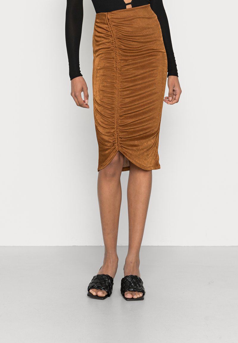 Saia midi de cor ferrugem com design franzido, feita de tecido suave, apresentando uma bainha com fenda. Combinada com sandálias de slide trançadas pretas.