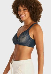 Marineblauwe bh met doorschijnende bloemenkantdetails en vaste stoffen cups. Beschikt over verstelbare bandjes en een zachte textuur.