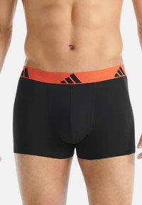 Zwarte boxershorts met een elastische oranje tailleband met zwarte logo-accenten. Zacht, glad materiaal met een aansluitend ontwerp.