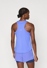 Μωβ αθλητικό τοπ χωρίς μανίκια με στρογγυλή λαιμόκοψη, λεία υφή και ανακλαστικές λεπτομέρειες στην πλάτη, συνδυασμένο με σορτς σε ταιριαστό χρώμα.