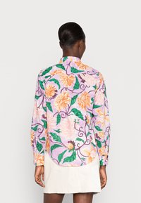 Chemise florale à manches longues en lavande, avec des fleurs orange et roses et des feuilles vertes, et une coupe fluide. Vue de dos montrant un ourlet arrondi.