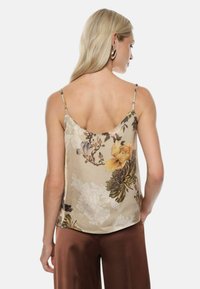 Camisola in satin con motivo floreale in beige, dotata di spalline sottili regolabili e design con scollo a barca. Texture liscia e silhouette fluida.