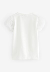 T-shirt en coton blanc avec des manches bouffantes transparentes courtes, un col rond et un design simple et épuré sans motifs ni embellissements.