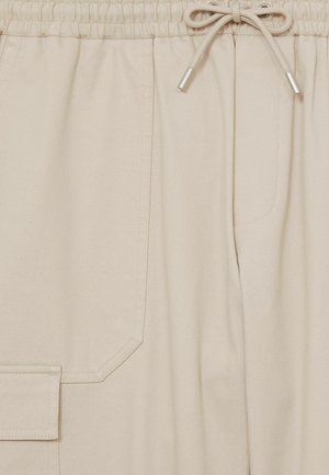 I pantaloni cargo beige presentano una vita con coulisse, tasche laterali e un tessuto liscio e testurizzato con dettagli di cucitura sottili.