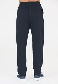 Mörkblå joggingbyxor med elastisk midja, sidofickor och avsmalnande ben. Tillverkade av mjukt tyg, lämpliga för avslappnad användning.