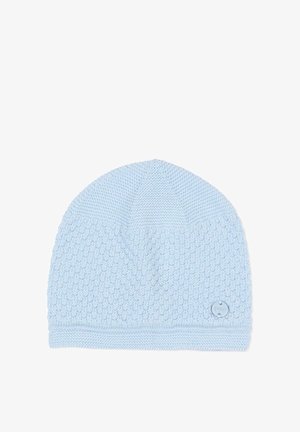 Bonnet en tricot bleu clair avec un motif texturé et une petite étiquette logo ronde près du bord, posé sur un fond blanc.