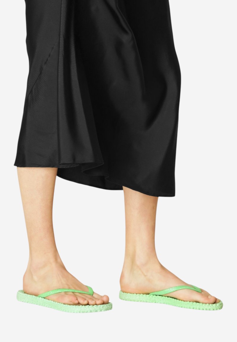 Groene flip-flops met een geweven gestructureerde zool en dunne bandjes. De zool heeft een gevlochten ontwerp, dat contrasteert met de gladde zwarte stof.