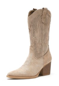Botas de vaquero de ante beige con diseño perforado, punta afilada y tacón apilado. Presenta costuras sutiles a lo largo del frente y una parte superior curva.