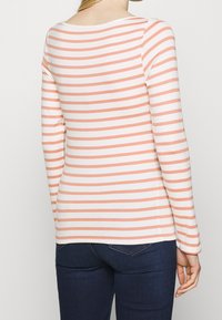 Randig långärmad topp i mjuk rosa och vit, med horisontella ränder, en rundad halsringning och figurnära silhuett.