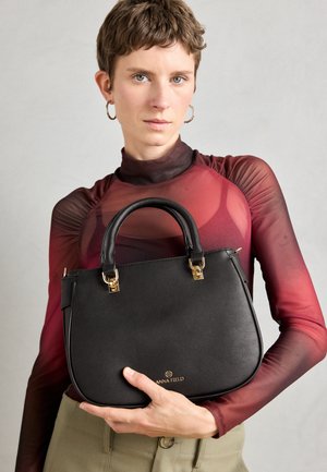 Bolso de cuero negro con herrajes dorados, parte superior redondeada y logotipo de la marca prominente. El bolso tiene una textura suave y una forma estructurada.