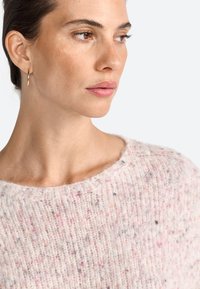 Rosa und beige gesprenkelter Strickpullover mit weitem Ausschnitt und geripptem Textur, kombiniert mit einem einfachen goldenen Creolenohrring.