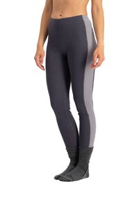 Frau trägt zweifarbige Leggings in Dunkel- und Hellgrau mit dunkelgrauen Socken, steht barfuß auf weißem Hintergrund.