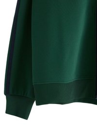 Grøn atletisk jakke med ribbede manchetter og en glat tekstur. Har en lynlåslukning foran og kontrasterende mørke sidepanel detaljer.